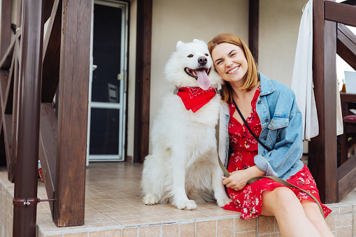 Woman with dog. Beaming fashionable woman feeling excited while coming to summer house with her dog