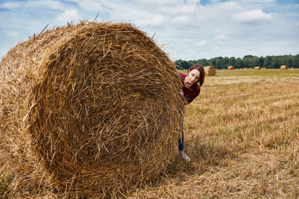 istock young girl having fun in the field, hiding behind a haystack 1027211996