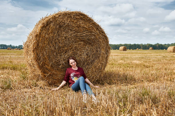 istock young girl having fun in the field, sits in a haystack and relaxing 1027212050