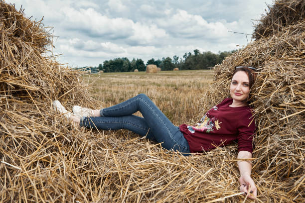 istock young girl having fun in the field, lying on a haystack 1027214932