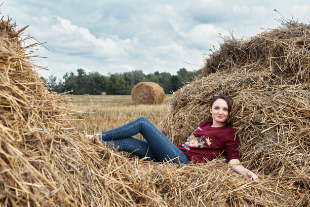 istock young girl having fun in the field, lying on a haystack 1027216352