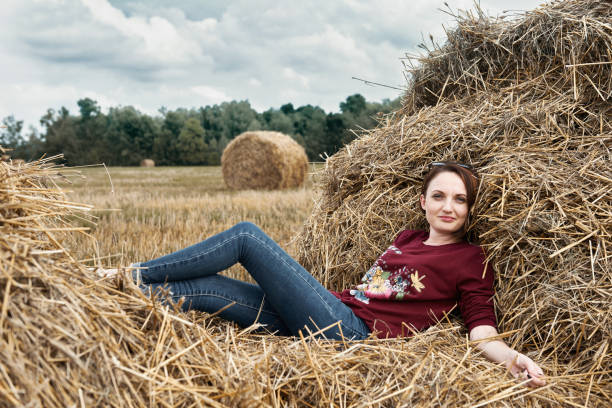 istock young girl having fun in the field, lying on a haystack 1027216374
