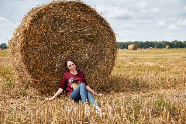 istock young girl having fun in the field, sits in a haystack and relaxing 1027218854