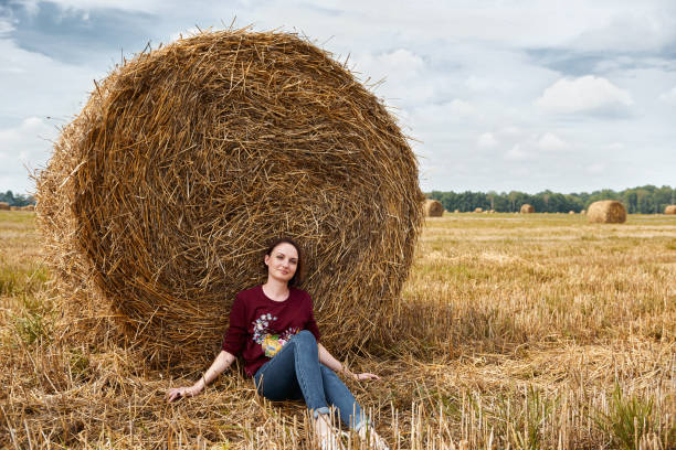 istock young girl having fun in the field, sits in a haystack and relaxing 1027219950