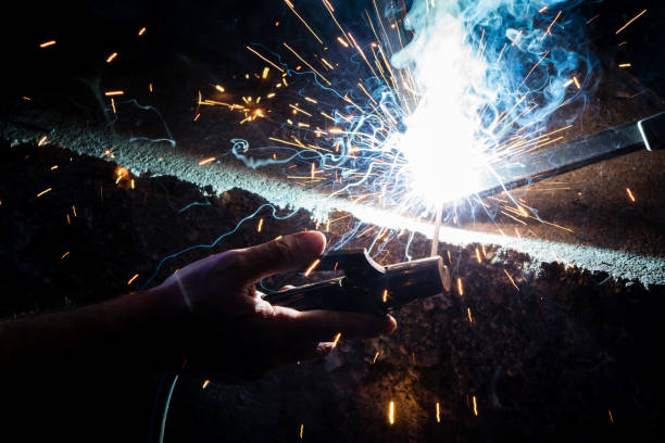 Man's hand welding steel with a sparks Man's hand welding steel with a sparks tehnical stock pictures, royalty-free photos & images