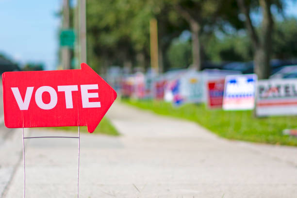 Vote Sign directing voters to polling place with political signs in the background polling place photos stock pictures, royalty-free photos & images