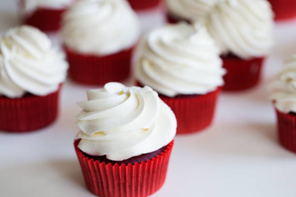 babeczki zwieńczone wirem słodkiego waniliowego lukieru. babeczki z czerwonego aksamitu - buttercream zdjęcia i obrazy z banku zdjęć