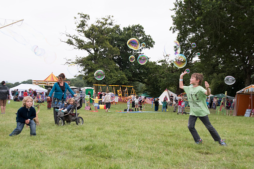 Chepstow, Wales-2013 Aug 14: Bubblemen at Work-2013 man creates giant bubbles for a crowd of children to children to play with and pop 14 Aug 2015 at The Green Gathering Festival