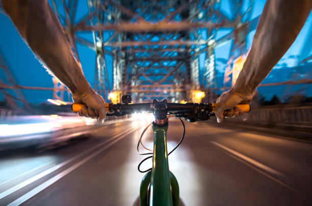 istock Cyclists ride at night over a bridge - FPV 1027255044