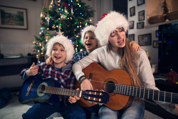Children singing Christmas carols near Christmas tree