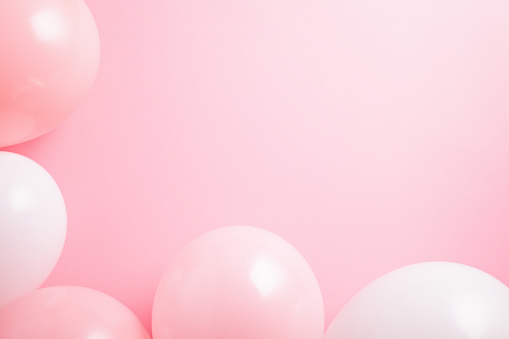 Party balloons and confetti border on pink background. Copy space
