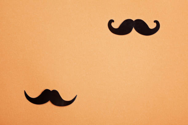 istock Black paper moustaches over orange background with copy space. 1027272742