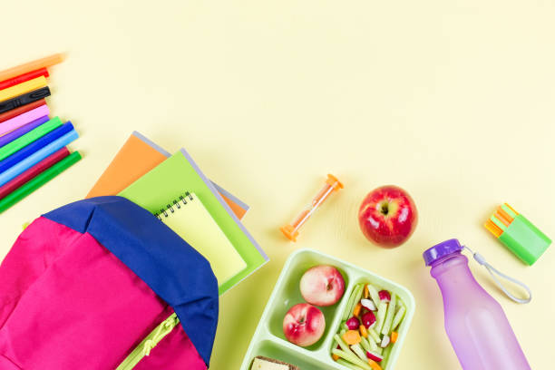 istock School concept flat lay. Kid backpack, lunchbox, water bottle, notebook, markers on wooden desktop 1027279664