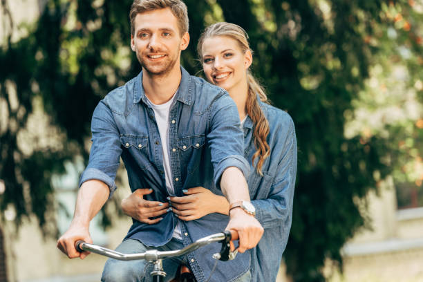 istock smiling young couple riding bicycle together at park 1027284452