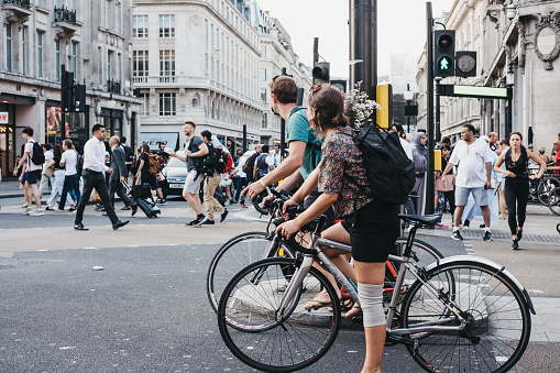 London, UK - July 24, 2018: Cyclists waiting for traffic lights on Oxford Street near entrance to Oxford Circus tube station, the busiest rapid-transit station in the United Kingdom.