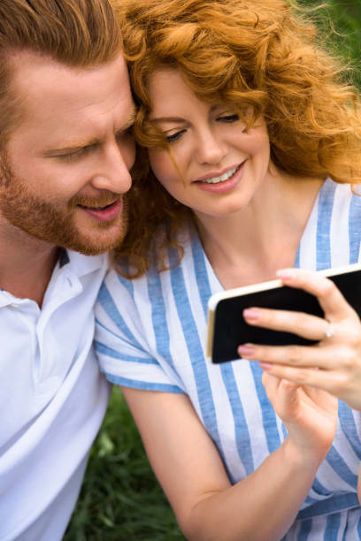 istock happy redhead couple looking at smartphone outdoors 1027302956