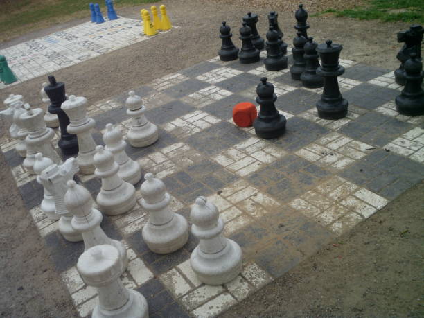 istock Scenic gigantic chess board with pieces outdoors and orange dice 1027303452