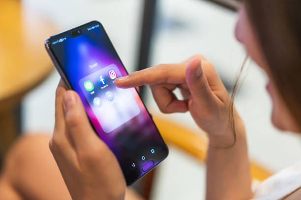 Asian woman using social media application on Huawei P20 pro smartphone, pointing at facebook app. Illustrative Editorial content. stock photo