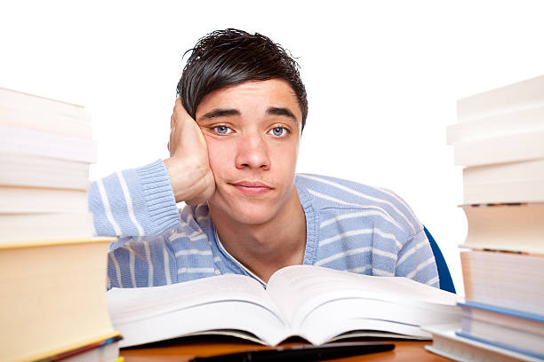 Young handsome male student sitting frustrated between study books stock photo