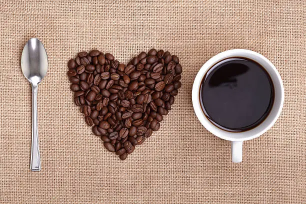 Photo of Spoon, heart-shaped pile of coffee beans, and cup of coffee