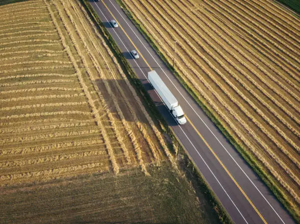 Aerial view of freight transportation truck 18 wheeler tractor trailer on rural highway near farm