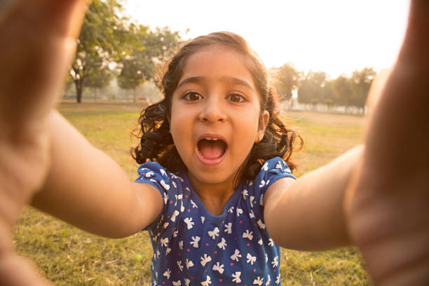 istock Happy little girl sitting on grass - Stock image 1027336474