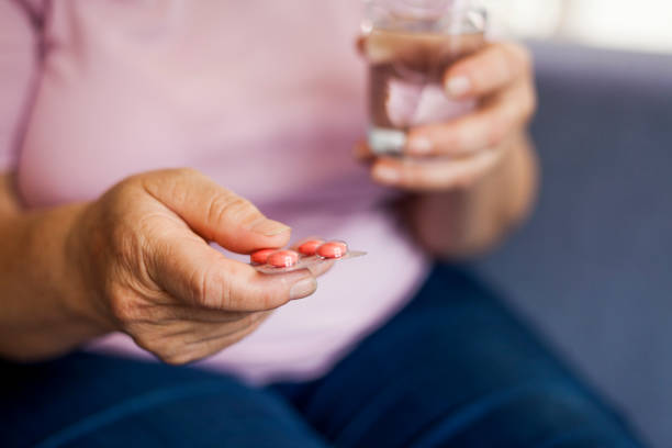 istock senior woman drinking pills 1027338734