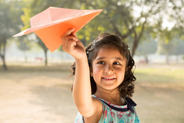 Girl playing with paper airplane - Stock image Girls, One Girl Only, Child, Activity, Caucasian Ethnicity paper airplane photos stock pictures, royalty-free photos & images