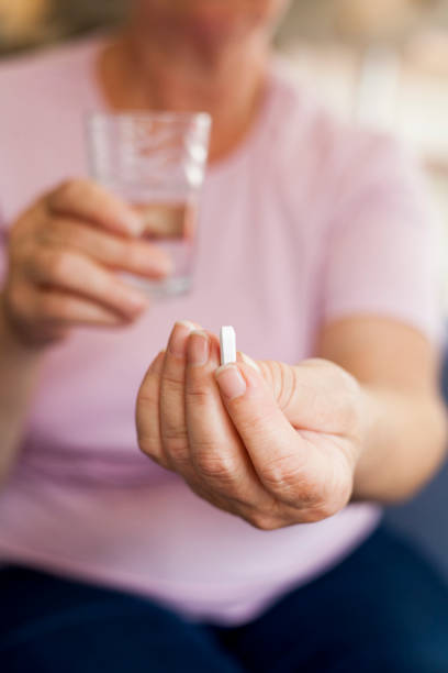 istock senior woman drinking pills 1027342490