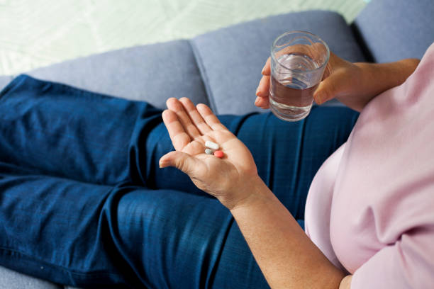istock senior woman drinking pills 1027342596