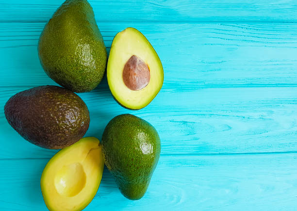 авокадо созрел на синем деревянном фоне - avocado brown стоковые фото и изображения