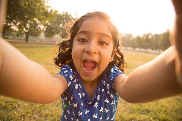 istock Happy little girl sitting on grass - Stock image 1027347468