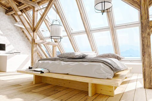 Interior of a Scandinavian style attic bedroom with beautiful sea and mountain view.