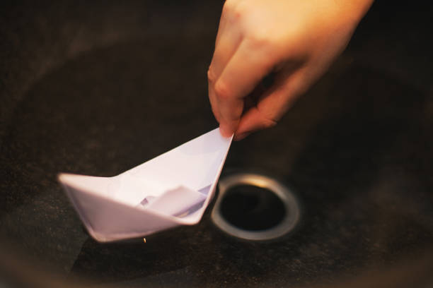 Young Boy Playing with Paper Boat in Sink