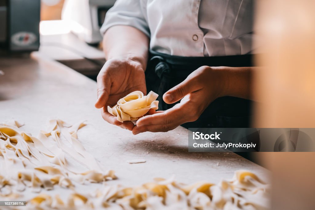 Chef woman's hands making pasta Chef woman's hands making tagliatelle pasta. Cooking process. Raw food photography concept. Pasta Stock Photo