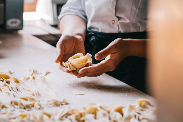 Chef woman's hands making pasta Chef woman's hands making tagliatelle pasta. Cooking process. Raw food photography concept. noodles stock pictures, royalty-free photos & images