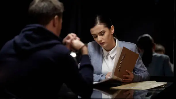 Young female police officer comparing suspect statements with file documents