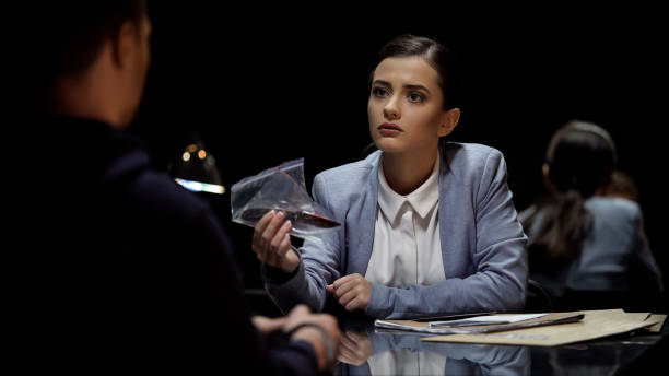 istock Attractive lady interrogator demonstrating bloody knife evidence to suspect 1027397138