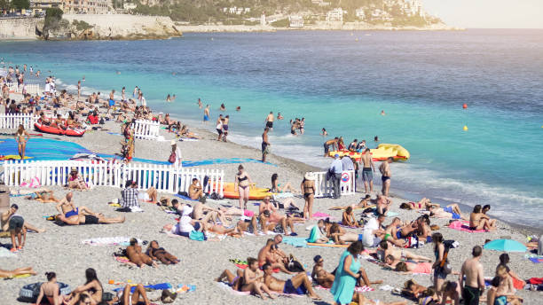 istock Crowded public beach at seashore, many people sun tanning, splashing in water 1027397402