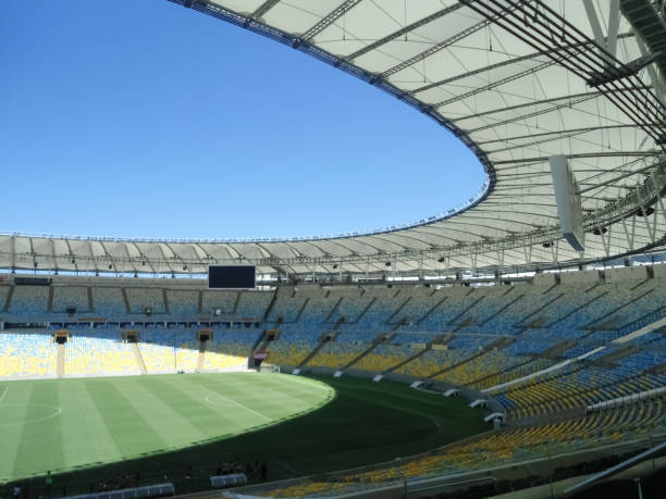 Maracana Stadium located in Rio de Janeiro (Brazil). Empty soccer field. Interior view of the Maracana Stadium. An impressive stadium located in the city of Rio de Janeiro (Brazil). Blue and yellow chairs, green soccer field and blue sky with detail of the structures. maracanã stadium stock pictures, royalty-free photos & images