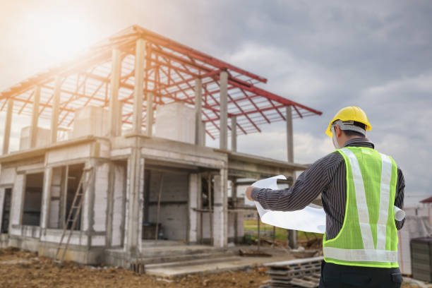 istock Professional engineer architect worker with protective helmet and blueprints paper at house building construction site 1027407126