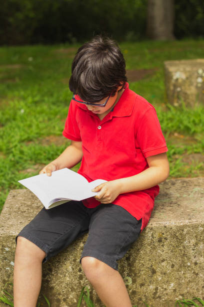 istock Cute boy reading a book at the park 1027409518