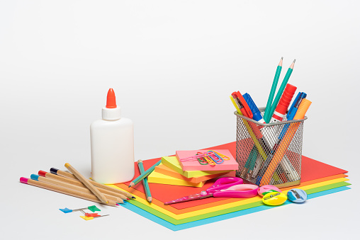 White background with stationery items - paper, pens, sharpeners, scissor, glue, paper clip , sticky notes and paper