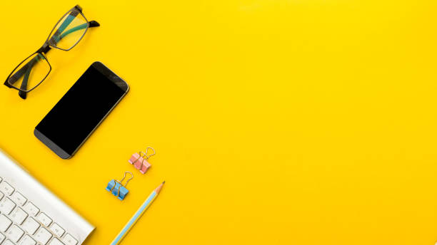 istock Mock up smartphone and office accessories on yellow background with copy space.view from above 1027418478