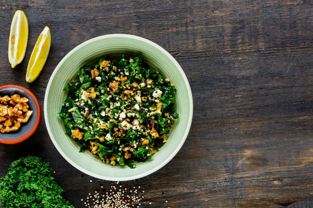 Kale and quinoa salad Close up of detox salad bowl. Healthy raw kale and quinoa salad with feta cheese and walnut on wooden background. Top view. Flat lay. Clean eating, dieting, vegetarian food concept grain bowl stock pictures, royalty-free photos & images