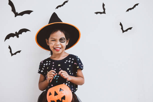 glückliche kleine kind asiatin in kostüme und make-up, die spaß am halloween-feier - maskenkostüm stock-fotos und bilder