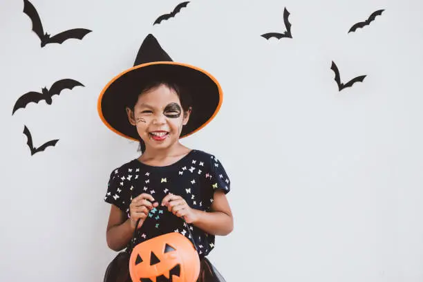 Happy asian little child girl in costumes and makeup having fun on Halloween celebration