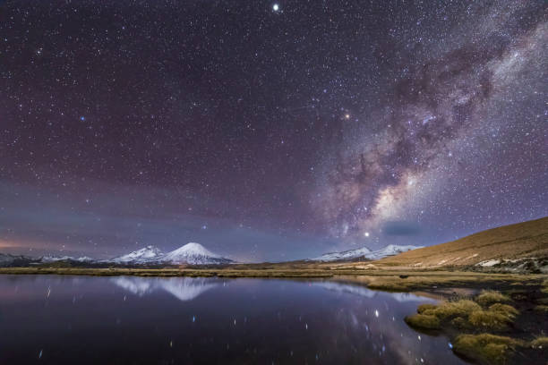 el gran "nevados de payachatas" pomerape y parinacota volcanes, izquierda y derecha respectivamente y el núcleo galáctico de la vía láctea subiendo desde el este sobre la laguna de cotacotani aguas, arica, chile - natural landmark winter season mountain peak fotografías e imágenes de stock