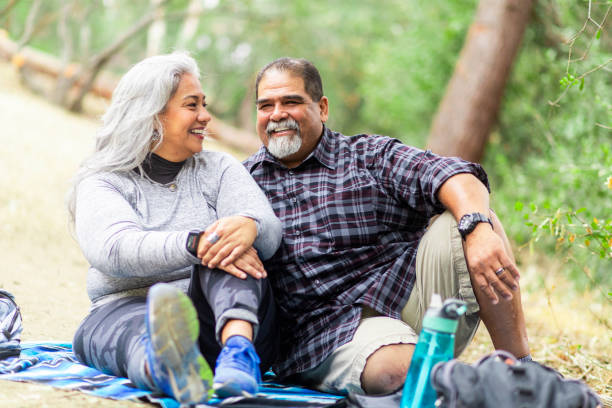 Senior Mexican Couple Having a Picnic A senior mexican couple enjoying a picnic on a blanket in the woods. fat mexican man pictures stock pictures, royalty-free photos & images