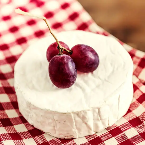 Cheese camembert on wooden desk, top view. Soft creamy cheese Brie with red grape